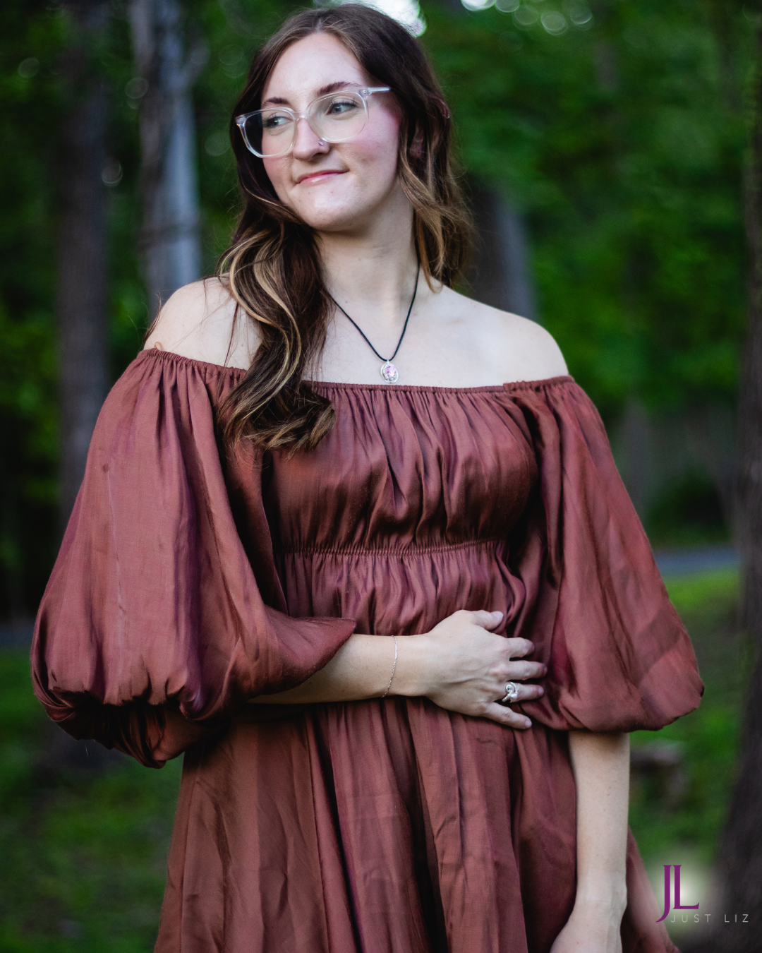 Woman smiling and wearing a round silver wire wrapped pink tourmaline necklace and a silver ring