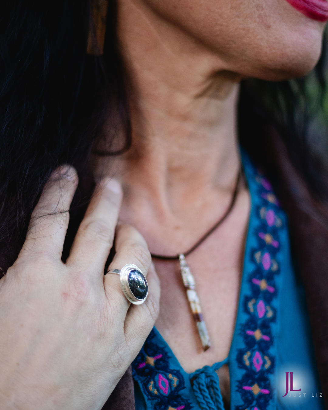 Woman wearing a big oval shaped hematite stone ring and a long thin jasper stone necklace