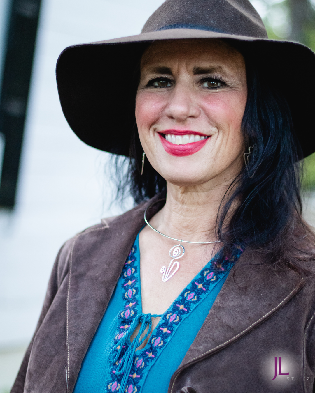 Woman smiling and wearing a silver wire flower shaped necklace