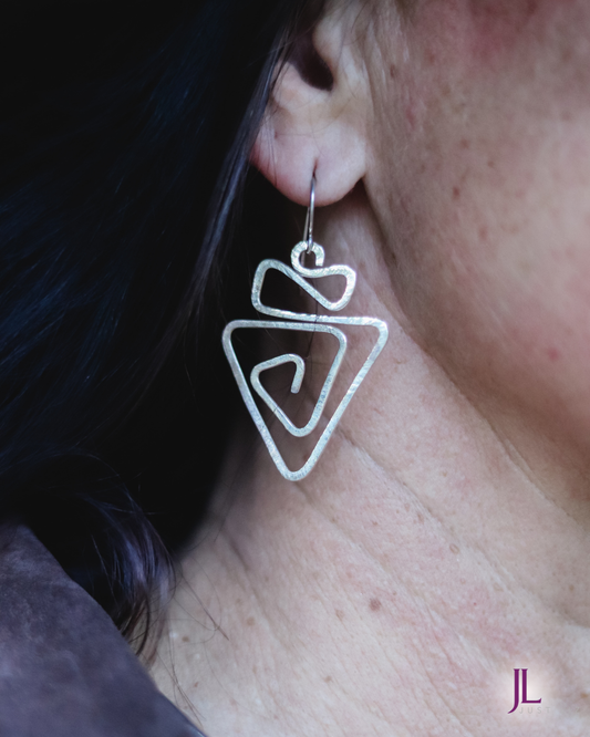 Woman wearing silver swirly geometric earrings