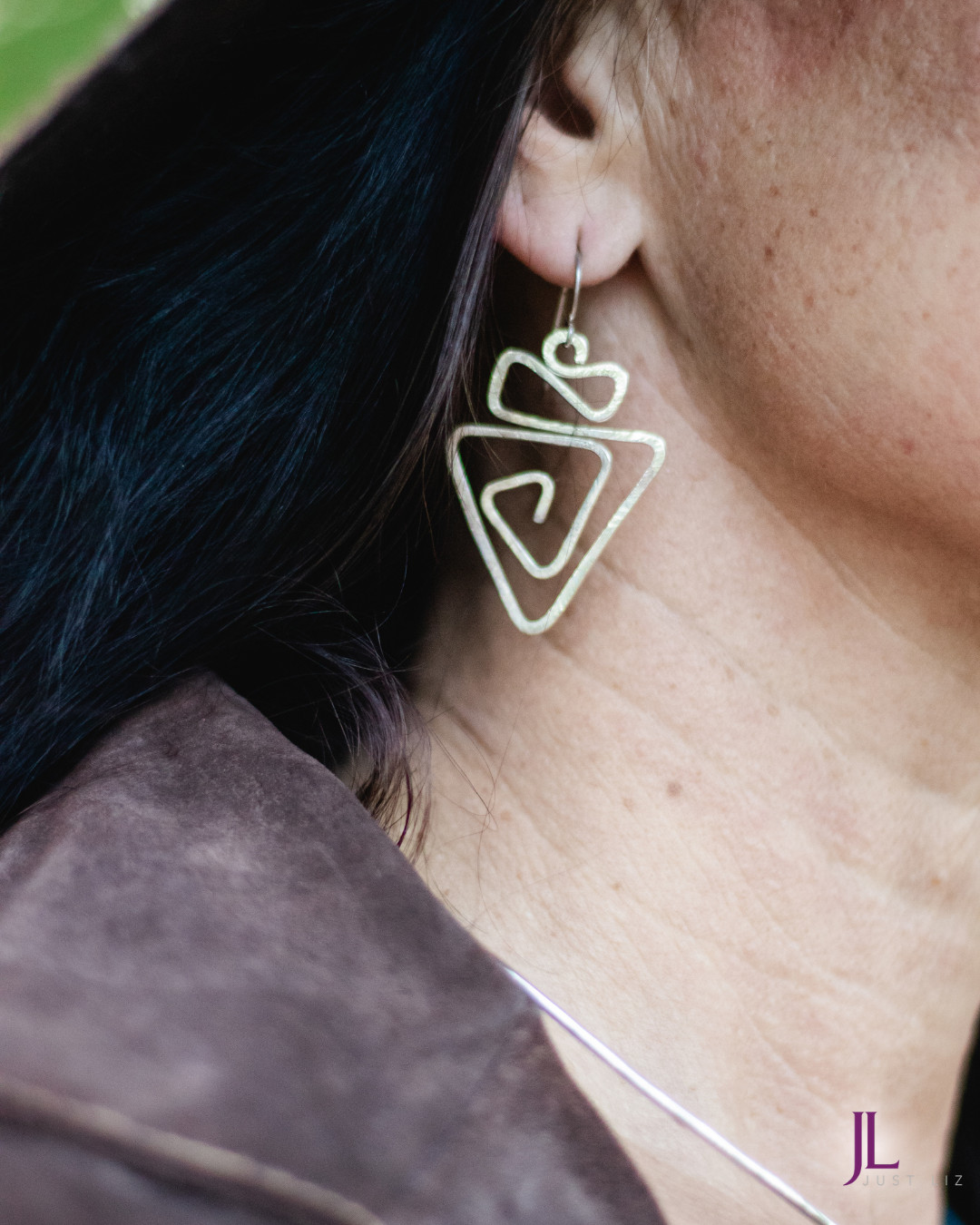 Woman wearing silver swirly geometric earrings