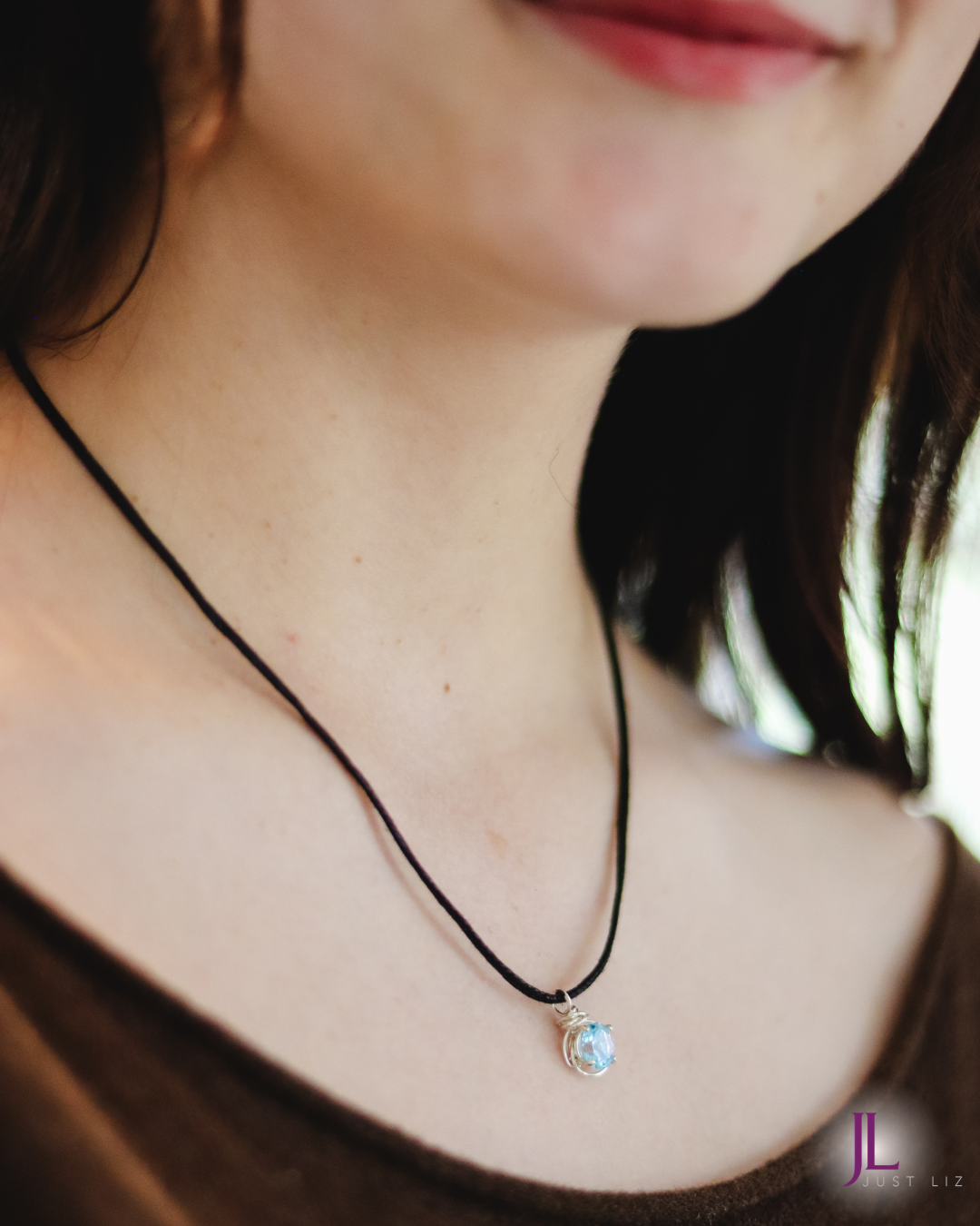 Woman smiling and wearing a blue topaz  necklace