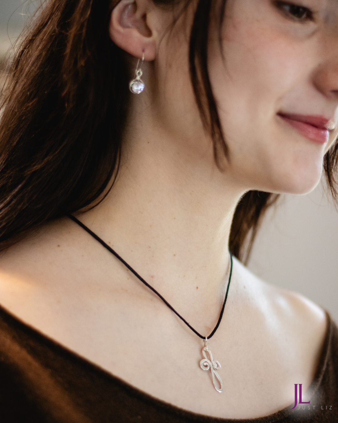 Woman wearing a swirly silver cross necklace