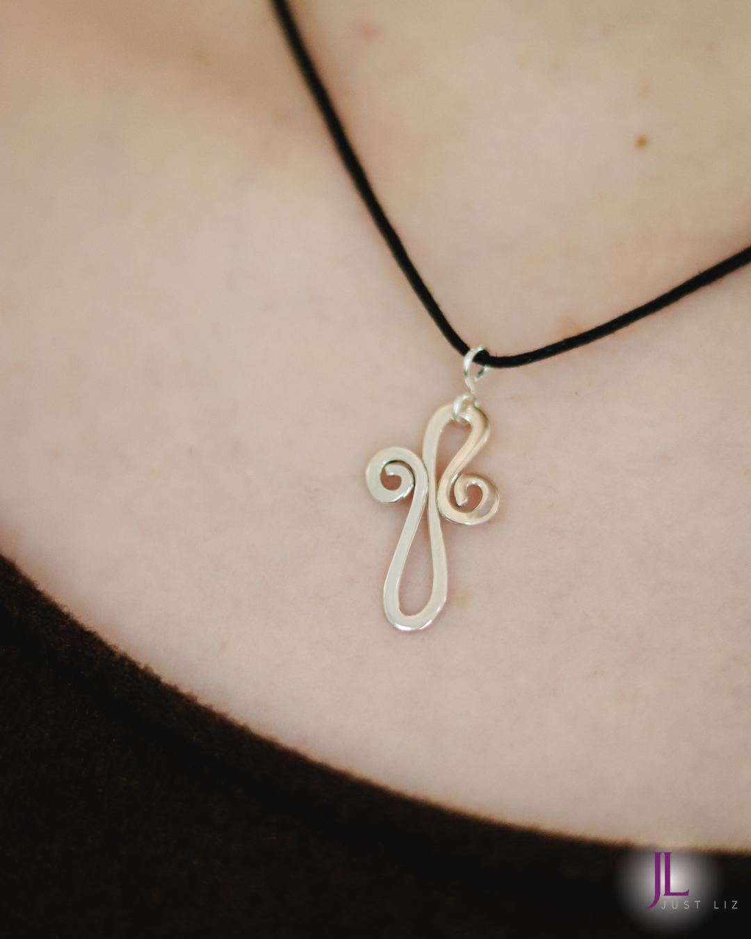 Woman wearing a swirly silver cross necklace