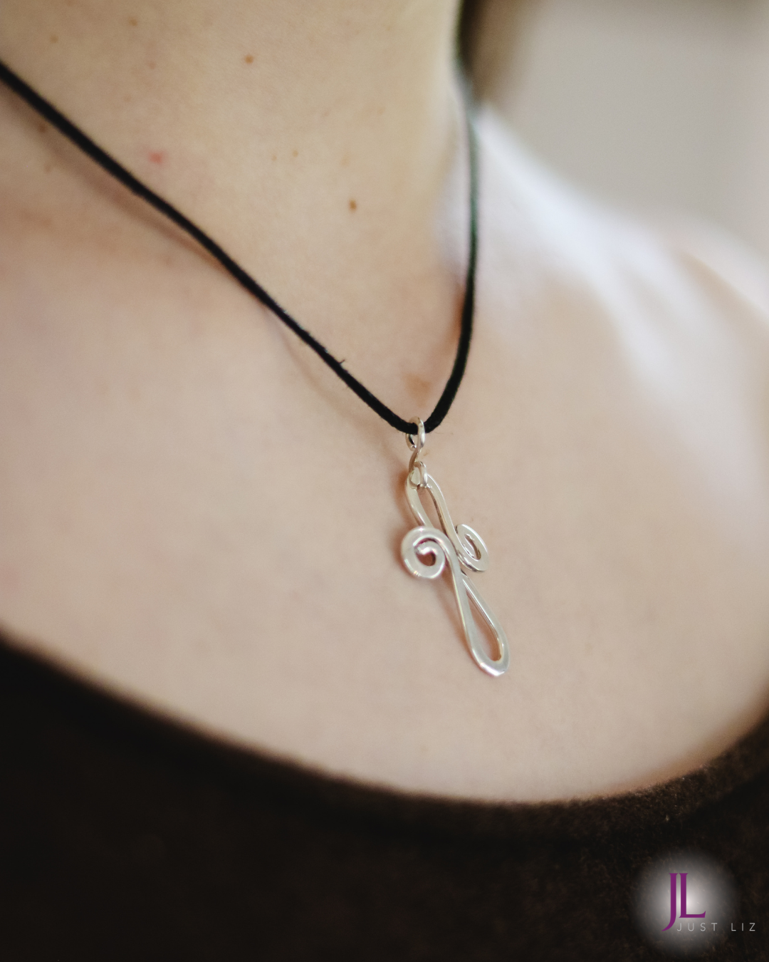 Woman wearing a swirly silver cross necklace