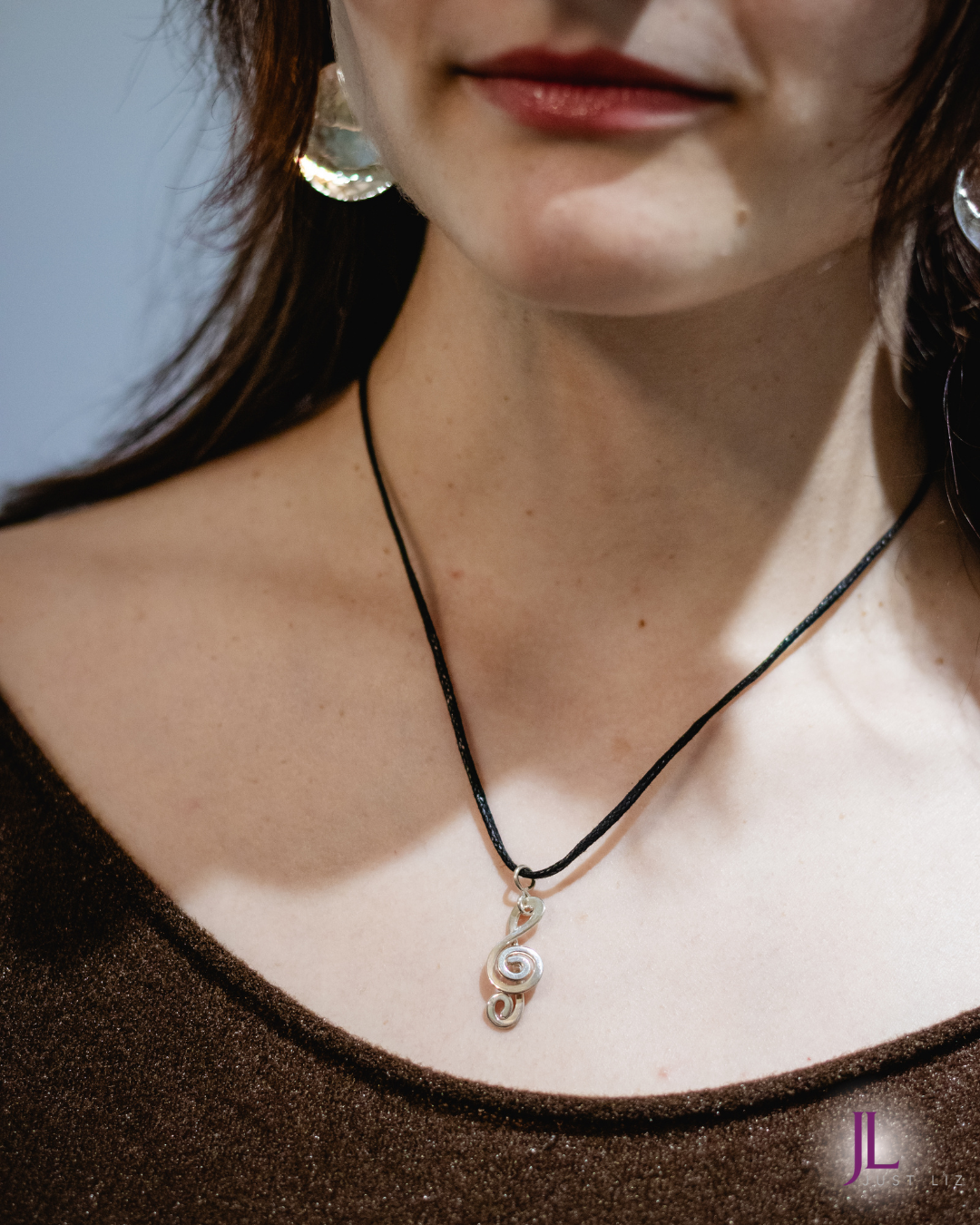Woman wearing a silver treble clef necklace and silver disk earrings