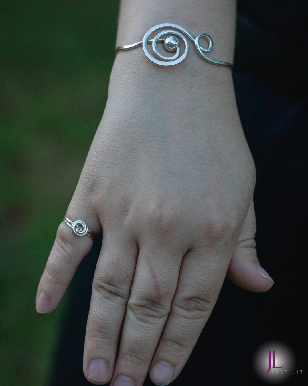 Woman wearing a silver music note bracelet and a small spiral silver ring