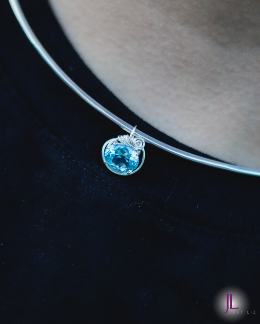 Woman wearing a small blue topaz pendant necklace