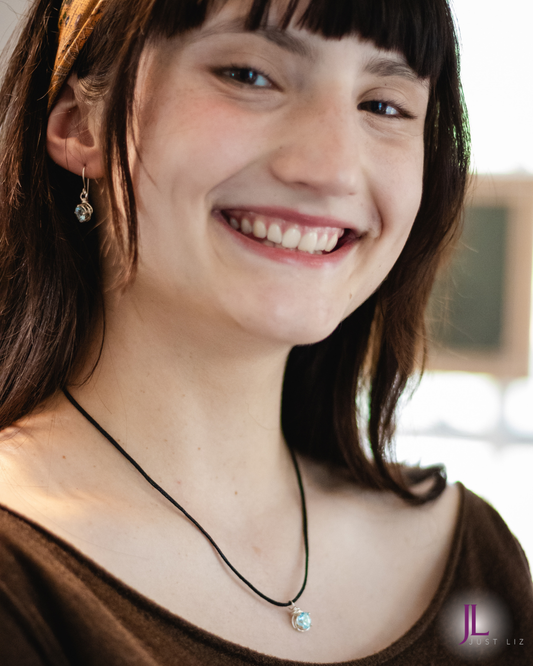 Woman smiling and wearing a blue topaz earring and necklace set