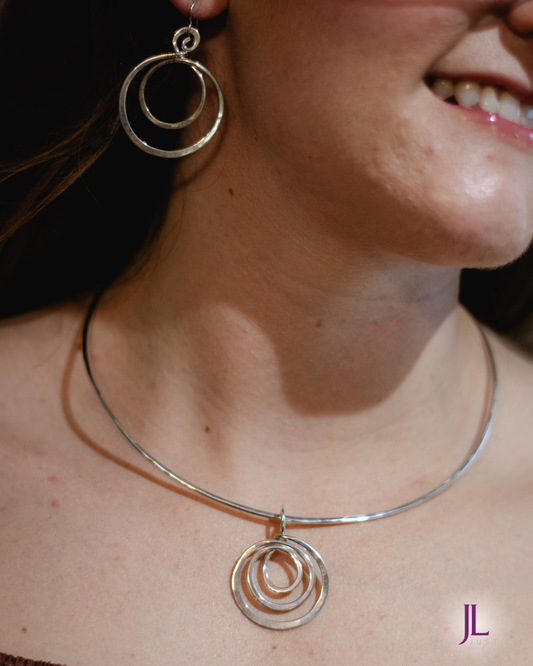 Woman wearing a silver spiral pendant collar necklace and matching spiral dangle earrings